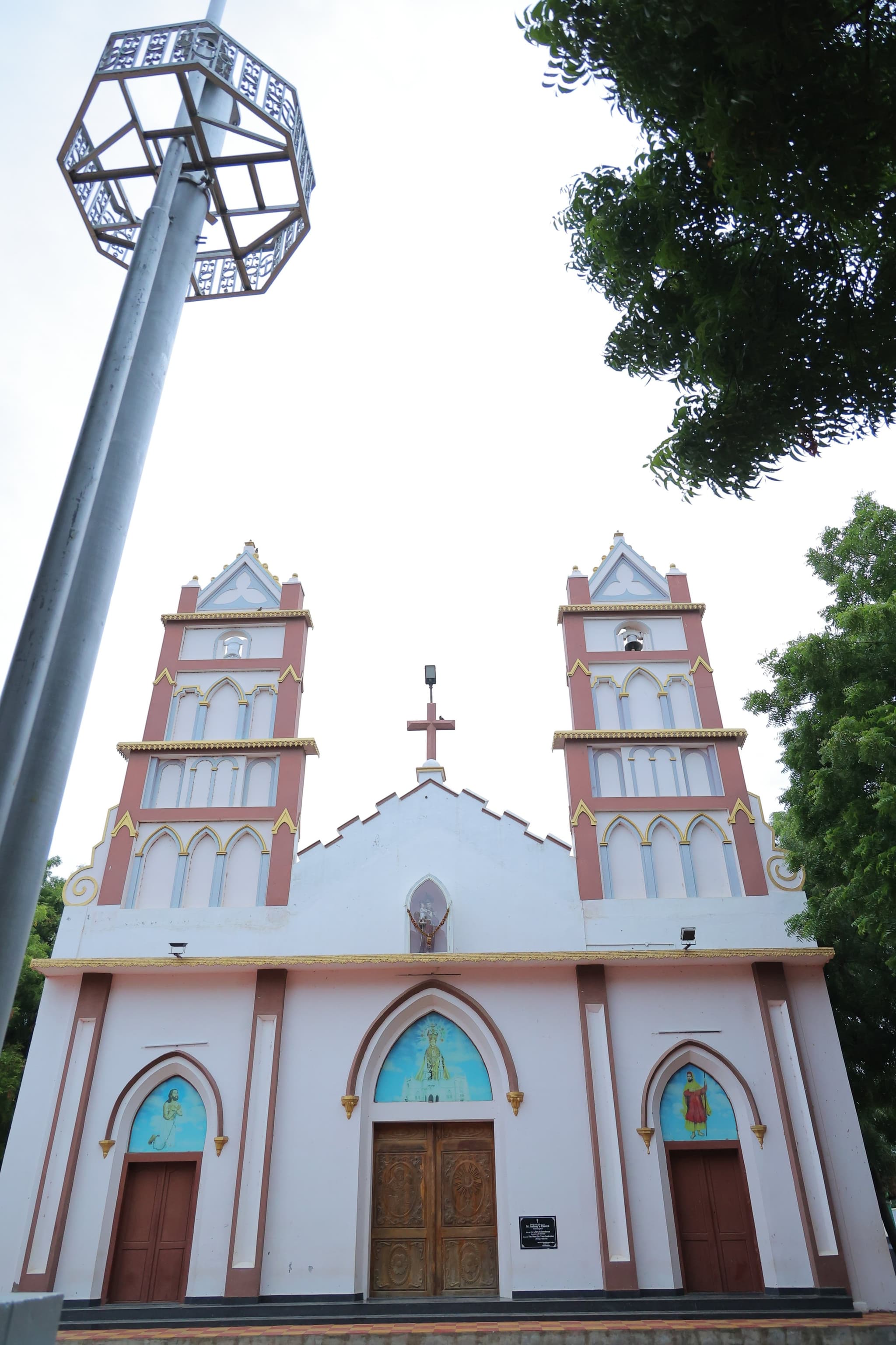St Anthony's church at Vadakkankulam — a pink-and-white front with two slender towers, a floodlight mast standing beside it