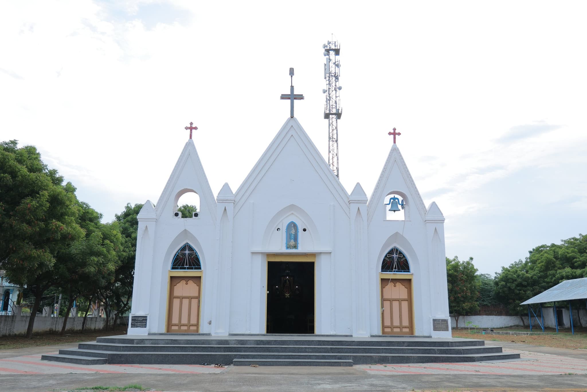 The Velankanni church of the parish — a white front stepped up to three crosses, with a broad flight of steps at the door