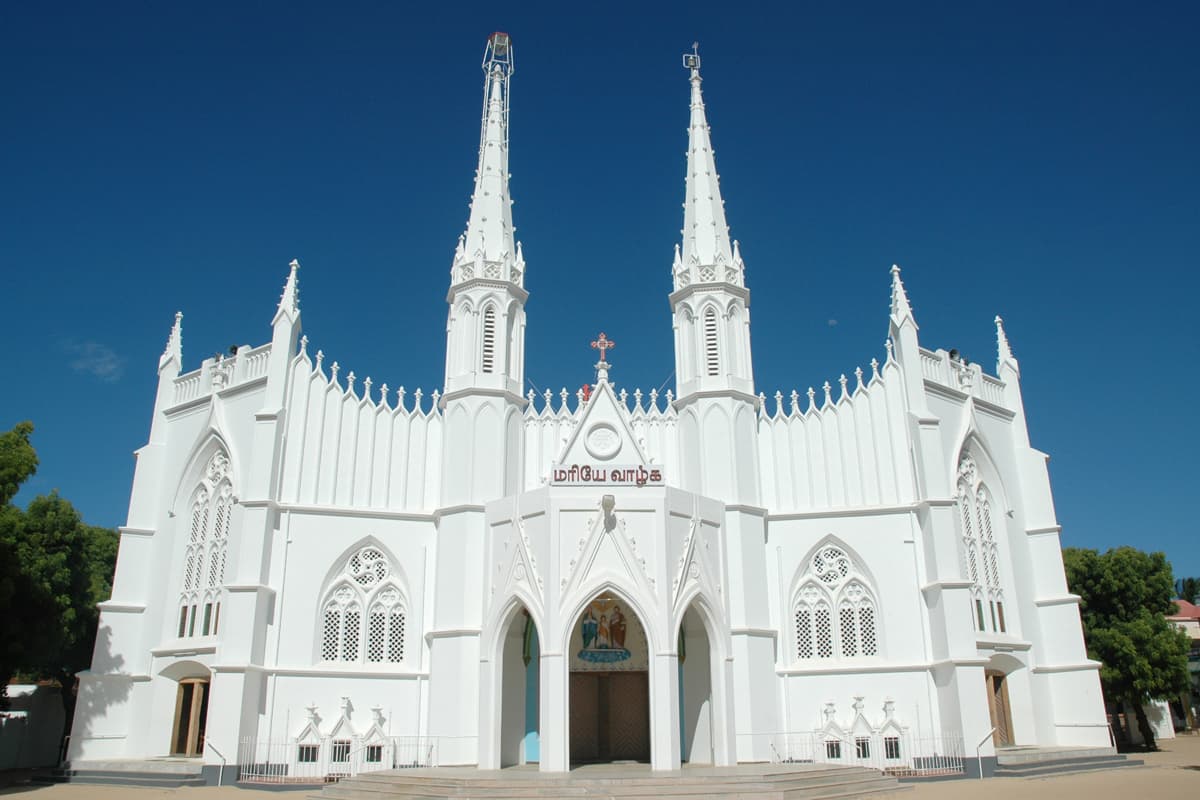 The white Gothic façade of the Holy Family Church, Vadakkankulam, with its twin octagonal towers and pinnacled roofline against a clear sky