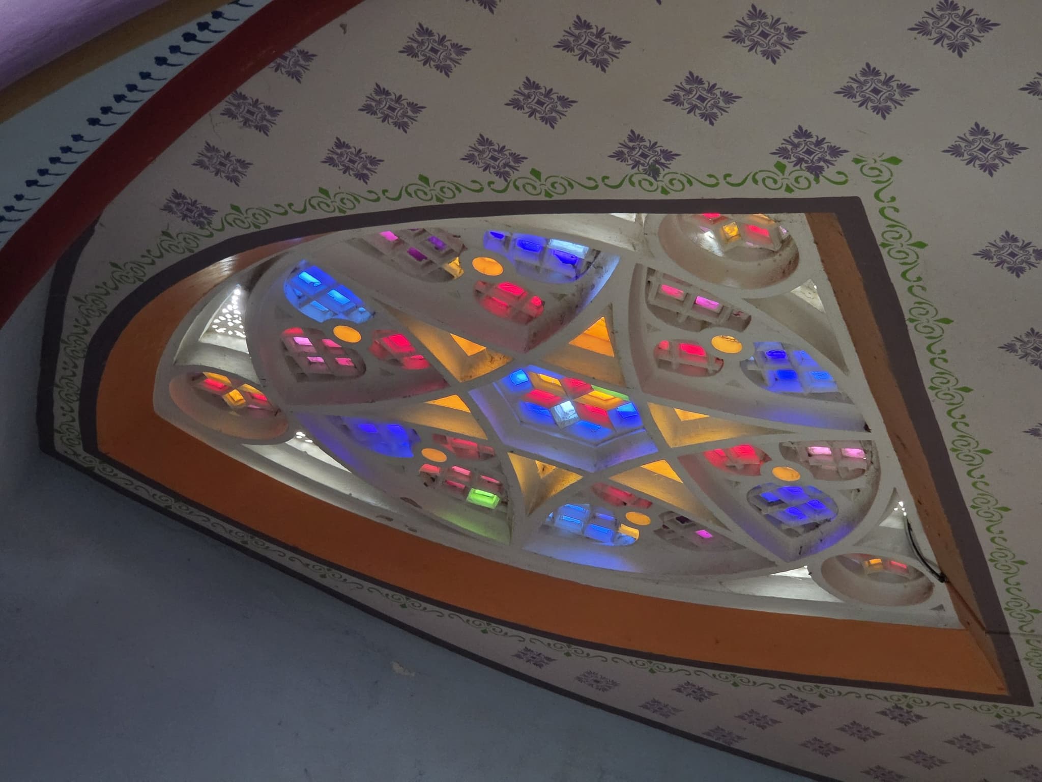 A rose window of jewelled glass set in painted vaulting